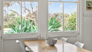 A room with a wooden table, white chairs, and a window with a view of green plants and trees. - 5 Rosetta Place, Hayborough (Hayborough)