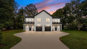 A two-story house with a large driveway, garage, and a covered porch. - Modern New Duplex in Prime Location (Haw River)