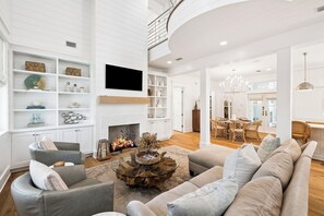 A spacious living area with a fireplace, modern furniture, and a dining area.