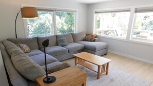 Un salon moderne avec un canapé d’angle gris, une table basse en bois et un lampadaire.