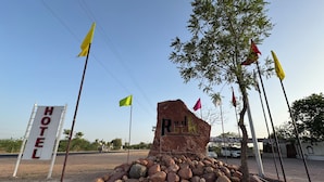 A hotel sign with a rock formation labeled "Red Rock" and multiple flags. - Red Rock Hotel & Restaurant (Bap)