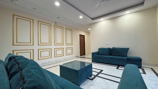 A modern living room with teal sofas, a glass coffee table, and a marble floor. - Red Rock Hotel & Restaurant (Bap)