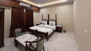 A bedroom with a four-poster bed, a desk with a chair, a ceiling fan, and an air conditioning unit. - Red Rock Hotel & Restaurant (Bap)