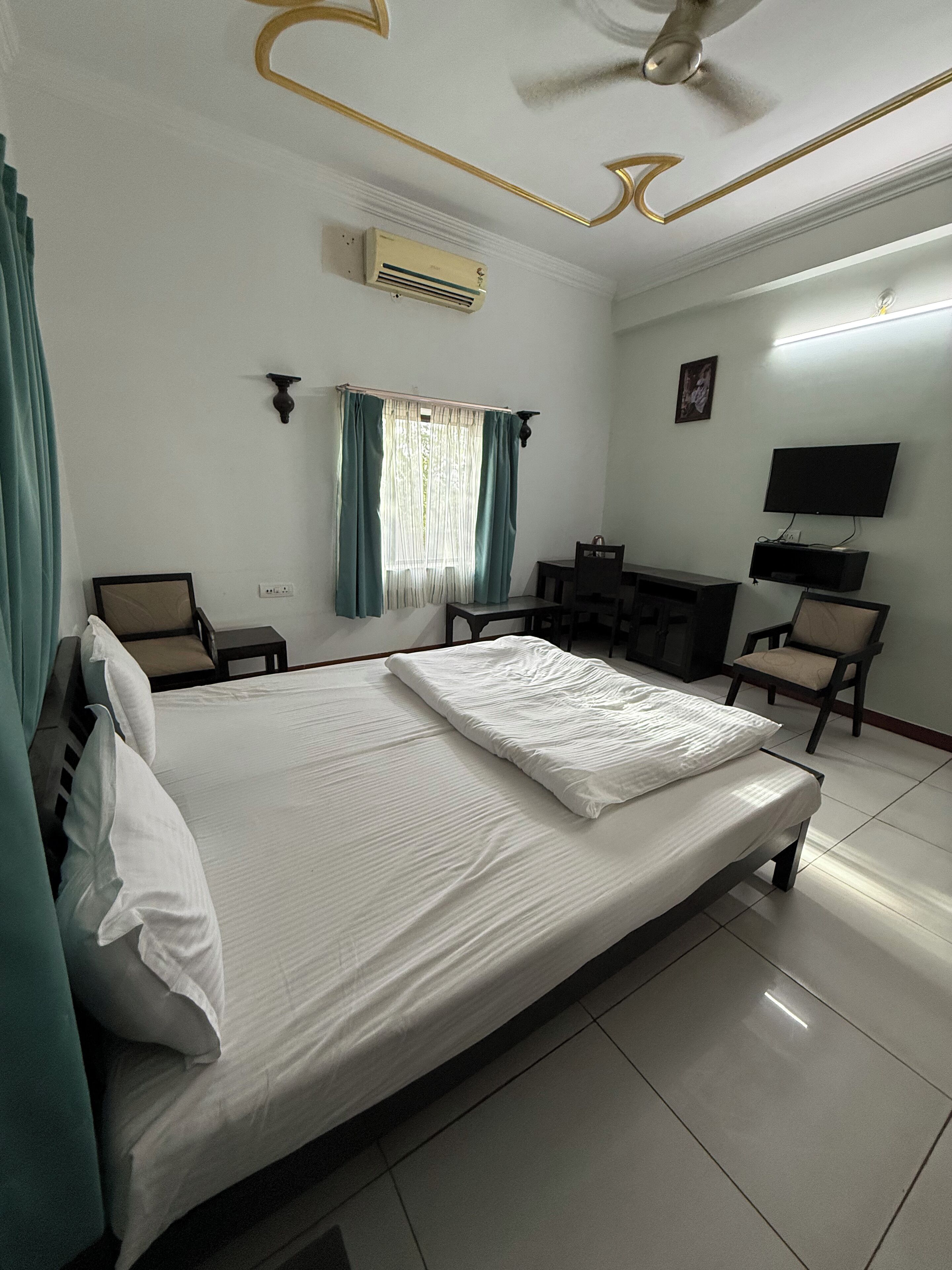 Una habitación de hotel con una cama, dos sillones, un escritorio, un televisor y un equipo de aire acondicionado.