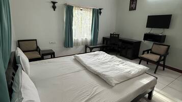 Una habitación de hotel con una cama, dos sillones, un escritorio, un televisor y un equipo de aire acondicionado.