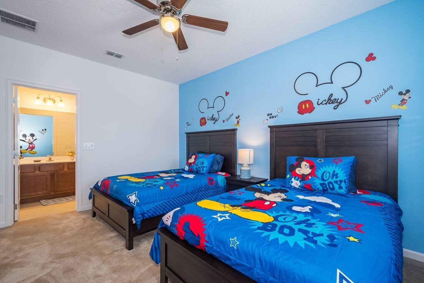 Une chambre avec deux lits, chacun agrémenté de linge de lit aux motifs de Mickey Mouse.