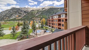 A balcony with a view of a mountain, a swimming pool, and a multi-story building with balconies. - Cs321 Copper Springs 1 Bedroom Condo (Copper Mountain)