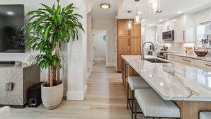 Una cocina moderna con una isla grande, armarios de madera y una planta en maceta.
