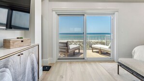 Una habitación con un amplio ventanal corredero que da a un balcón con vista a la playa.