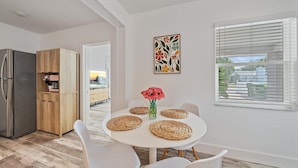 Een moderne keuken met een inbouwkoelkast, houten kastjes en een eethoek met een witte tafel en stoelen.