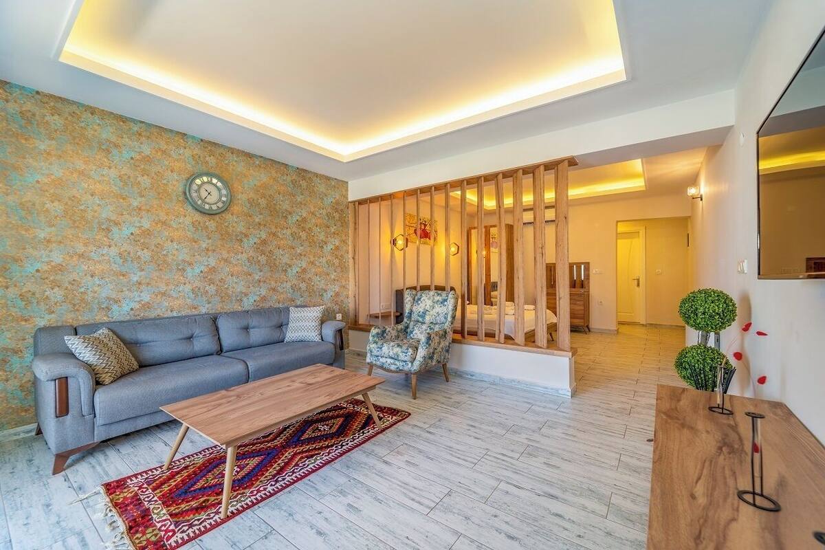 A modern living room with a grey sofa, patterned rug, wooden coffee table, and a decorative chair.