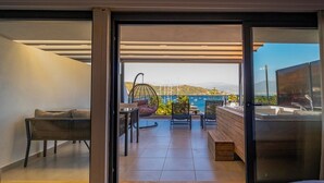 Ein modernes Zimmer mit einer Schiebeglasdoor zur einem Balkon mit Blick auf Meer und Berge.