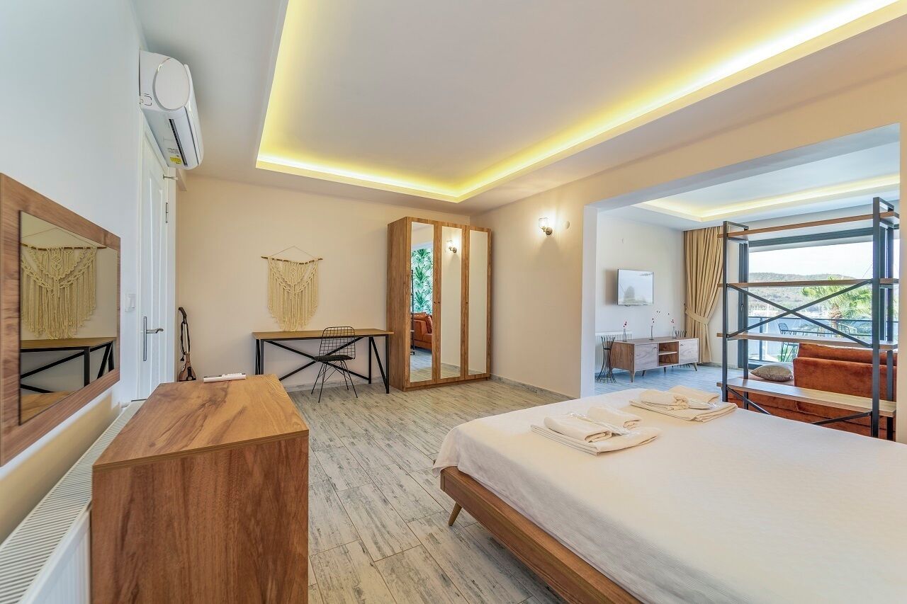 Een moderne hotelkamer met een groot bed, een bureau, een kledingkast en een balkon met uitzicht.