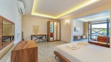 Een moderne hotelkamer met een groot bed, een bureau, een kledingkast en een balkon met uitzicht.