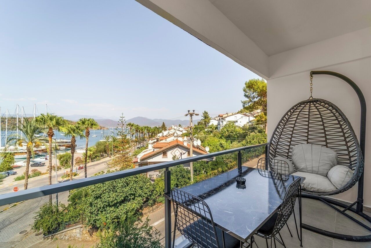 A balcony with a hanging chair, a table, and chairs.