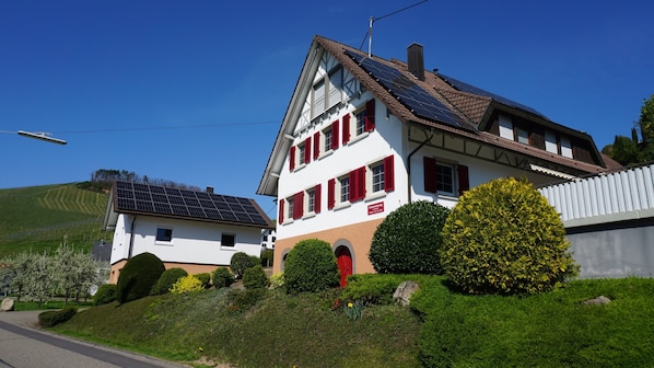 Une maison à deux étages dotée de panneaux solaires, d’une porte rouge et d’une enseigne indiquant qu’il s’agit d’un restaurant.