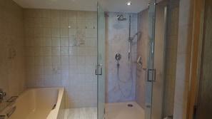 A bathroom with a bathtub, a glass-enclosed shower, and tiled walls.