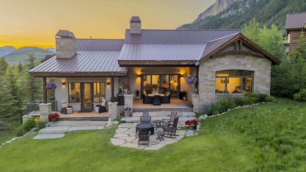 Une maison en pierre à deux étages, dotée d’un patio, d’un espace salon extérieur et offrant une vue sur les montagnes.