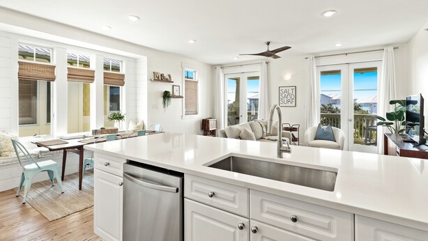 Una cocina moderna con muebles blancos, un lavamanos de acero inoxidable y una isla grande.
