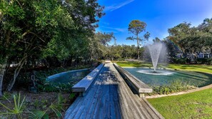 A wooden boardwalk leading to a fountain in a park with trees and a building in the background. - Seagrove "Beachbound" 1BR, Sleeps 4, Gulf Views, Private Beach Access (Santa Rosa Beach)