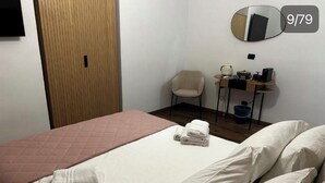 Une chambre d’hôtel avec un lit, une chaise, un bureau avec un ordinateur et un miroir.
