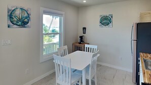 A kitchen with white cabinets, a black refrigerator, and a window with a view of greenery. - Blue Marlin #11 | Bay Views, Community Pool (Rockport)