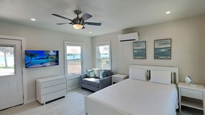Une chambre dotée d’un grand lit, d’un ventilateur de plafond, d’une télévision et d’une fenêtre donnant sur l’extérieur.