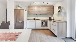 Eine moderne Küche mit hellen Holzschränken, einer Edelstahlspüle und einem eingebauten Backofen.