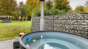 Ein Whirlpool mit Steinwand und Metallzaun in einem Garten.