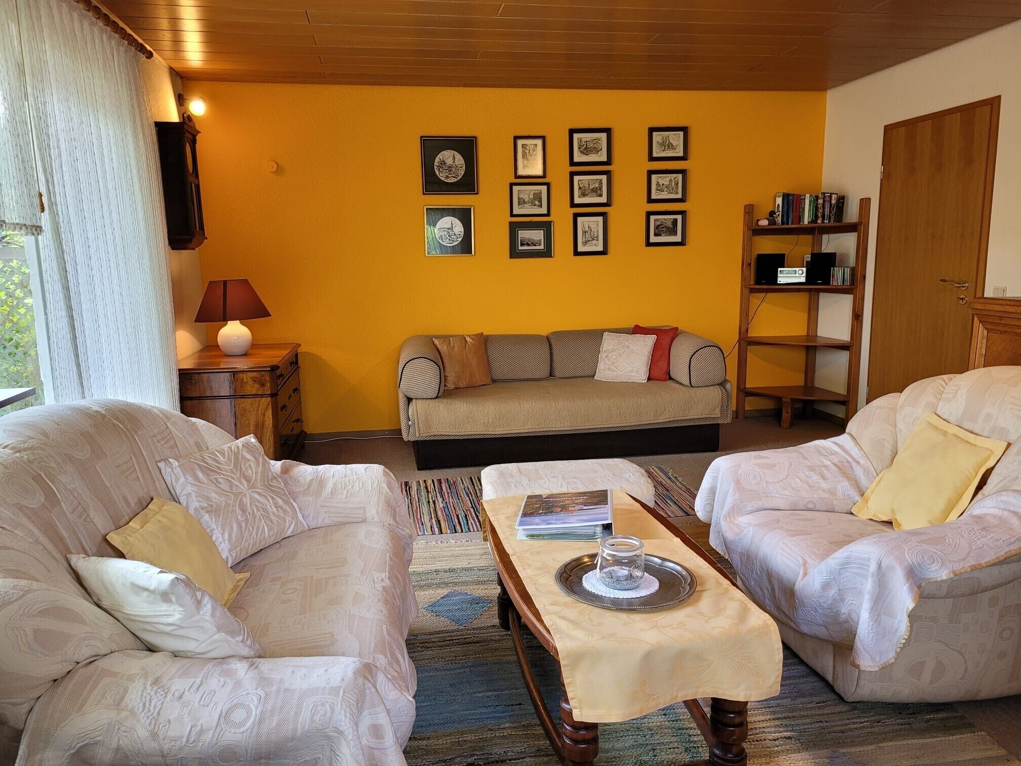 Een woonkamer met twee banken, een salontafel, een boekenkast en ingekaderde foto's aan de muur.