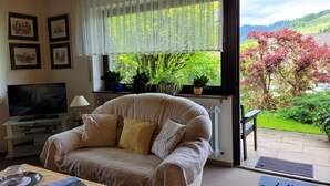 A living room with a sofa, television, and potted plants. - Apartment Ritter with Panoramic Valley View and Private Terrace (Oberharmersbach)