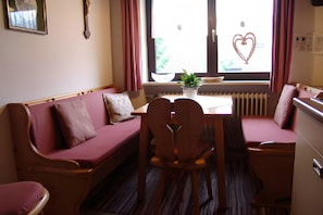 Ein gemütliches Zimmer mit einer Holzbank, einem kleinen Tisch und einem Fenster mit Herzverzierungen.