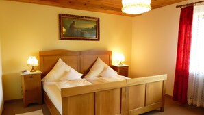 A wooden bed with two nightstands, a painting on the wall, and a red curtain. - Apartment Ritter with Panoramic Valley View and Private Terrace (Oberharmersbach)