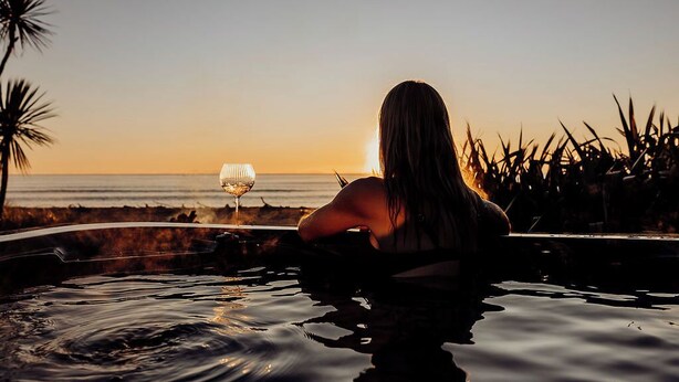 Eine Person im Pool mit Blick auf einen Sonnenuntergang.
