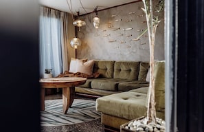 A living room with a green sofa, a round wooden coffee table, and a wall with fish decorations.