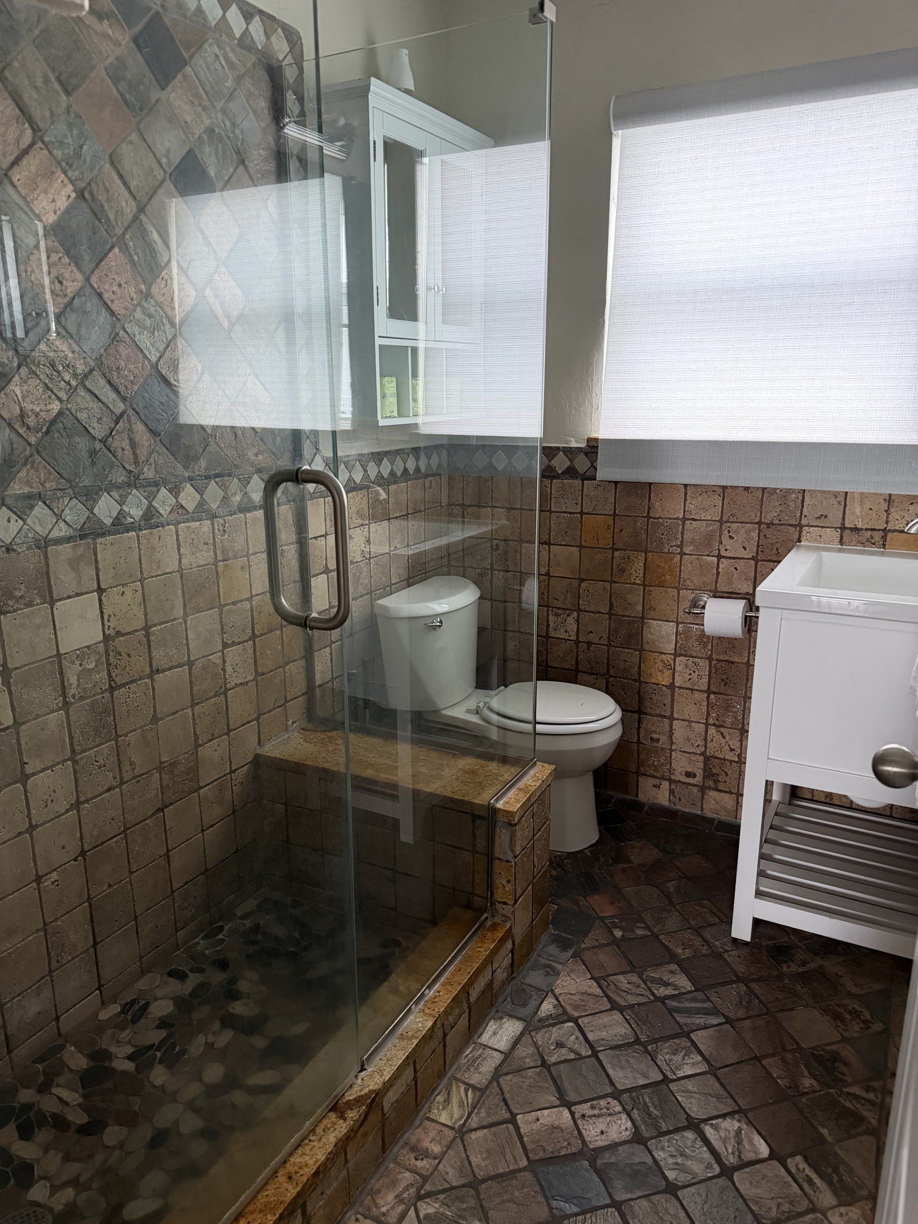 A bathroom with a shower enclosure, a toilet, and a sink.