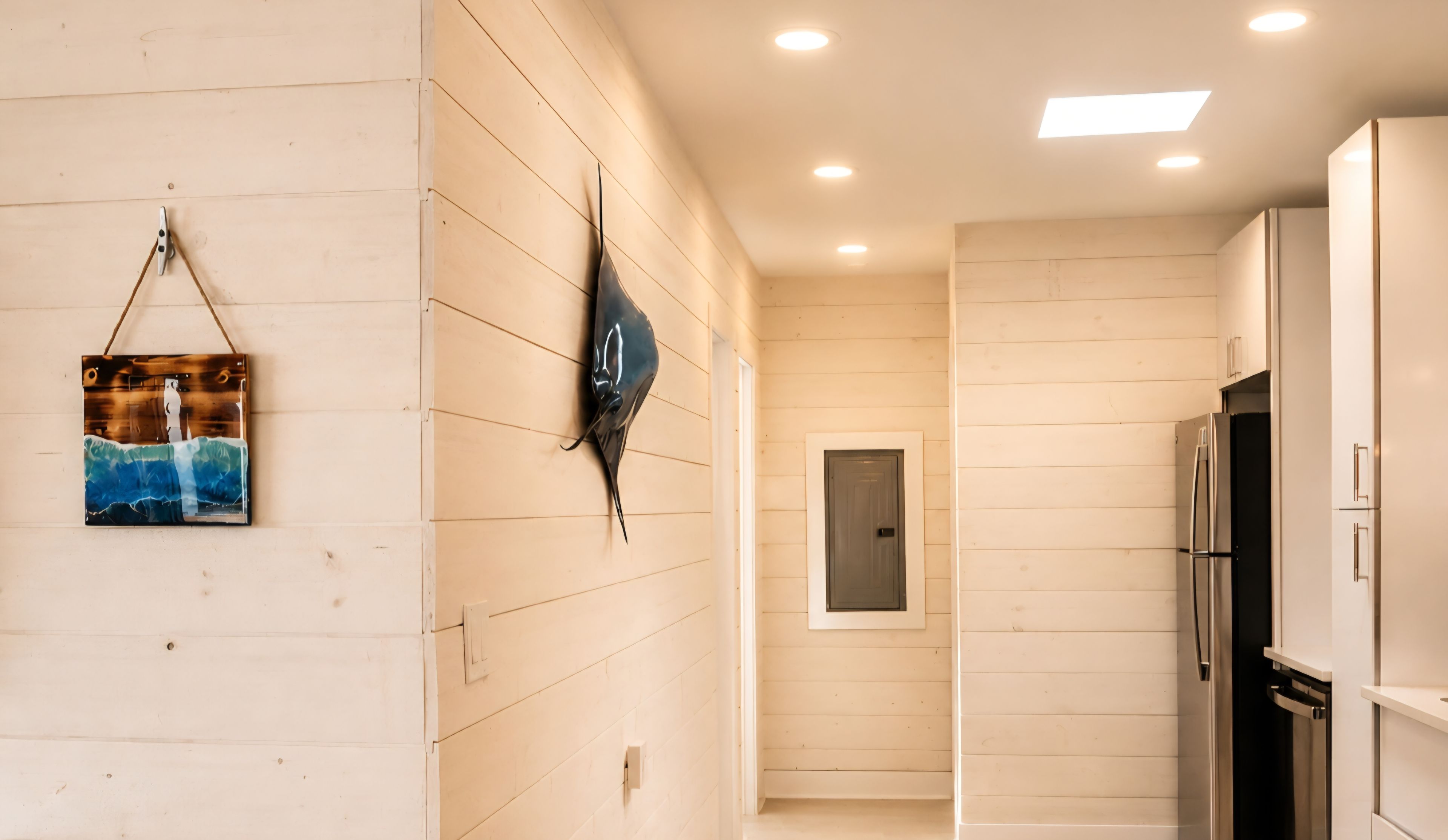 A modern kitchen with white cabinetry, a stainless steel refrigerator, and a wall-mounted light fixture.
