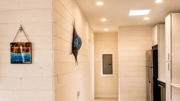 A modern kitchen with white cabinetry, a stainless steel refrigerator, and a wall-mounted light fixture.