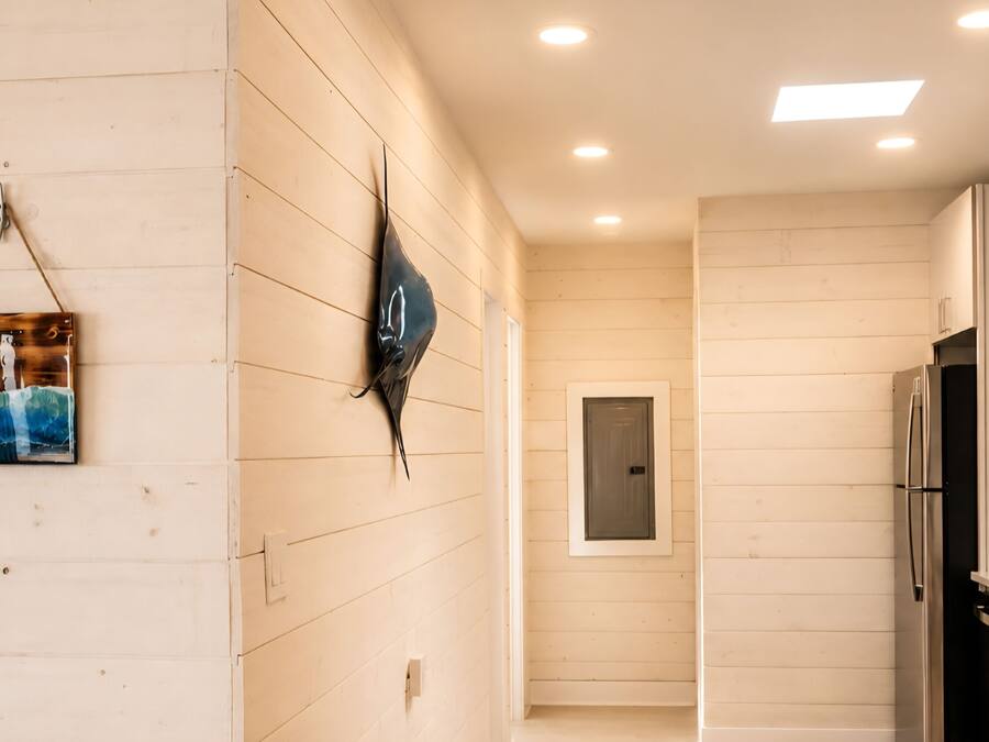 A modern kitchen with white cabinetry, a stainless steel refrigerator, and a wall-mounted light fixture.