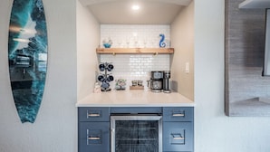 A kitchen with a white tiled backsplash, wooden shelves, and a built-in oven. - Blue Wave Suites (Clearwater Beach)