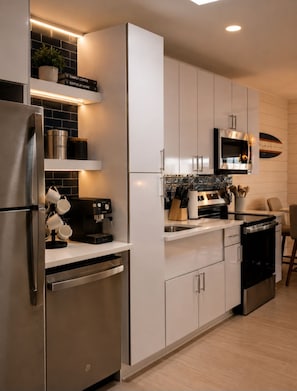 Een moderne keuken met roestvrijstalen apparatuur, een koffieapparaat en een magnetron.