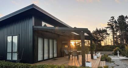 The open-plan kitchen, dining and lounge area is the heart of the home, perfect for sharing a meal, curling up with a good book, or simply watching the weather roll in through the floor-to-ceiling windows.