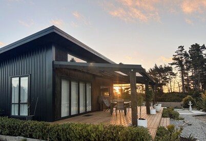 The open-plan kitchen, dining and lounge area is the heart of the home, perfect for sharing a meal, curling up with a good book, or simply watching the weather roll in through the floor-to-ceiling windows.