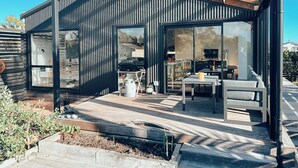 A modern house with a patio area, large windows, and a pergola. - Kowhai Cabin - Serene Scandi Escape in Hokitika (Hokitika)