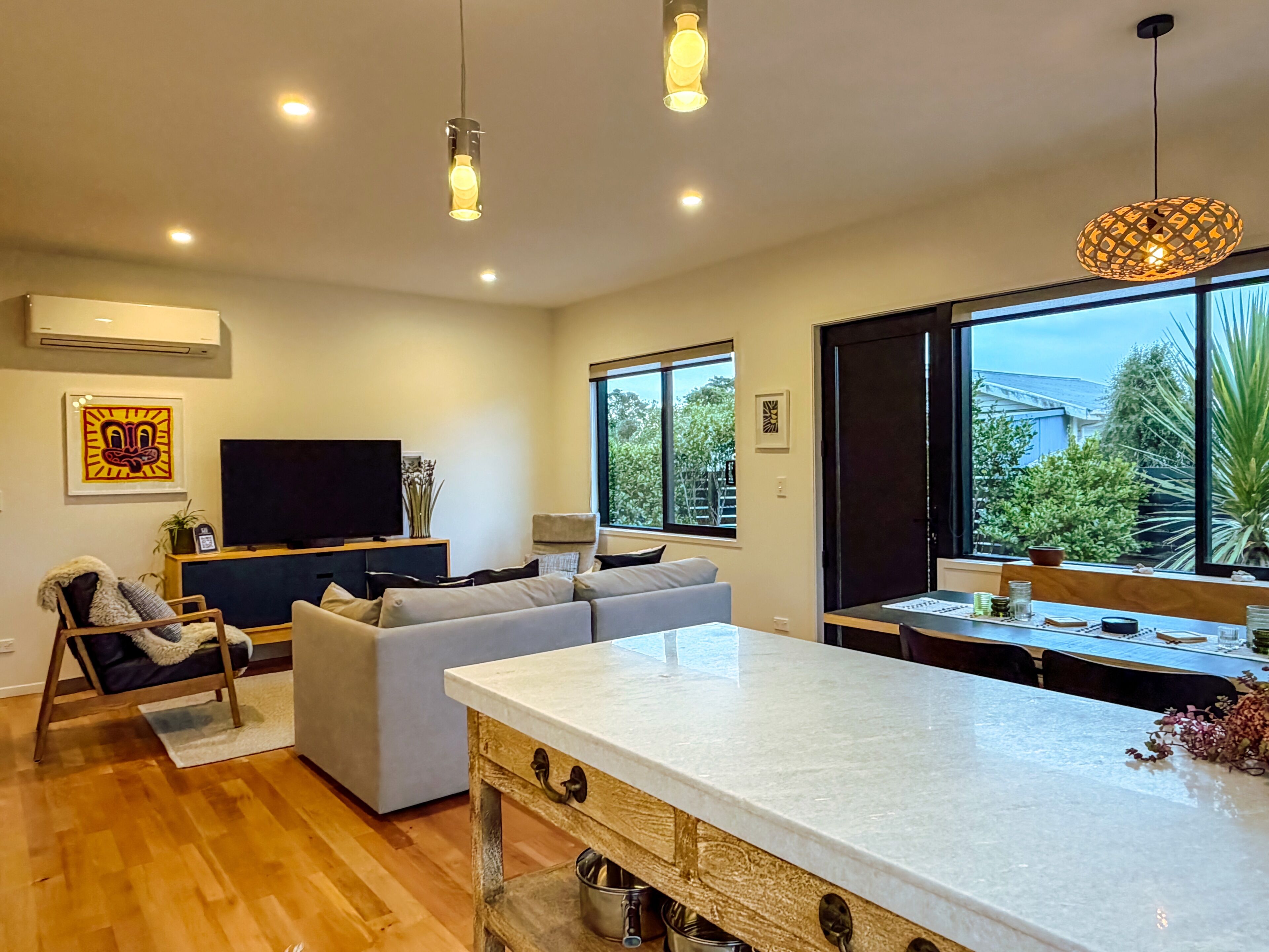 A modern living room with a sofa, a dining area with a table, and a kitchen with a marble countertop.