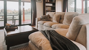 En hyggelig stue med en beige sofa, et mørkt træ sofabord og en reol.