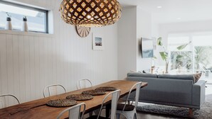 En matplats med ett träbord, vita stolar och en flätad hänglampa.