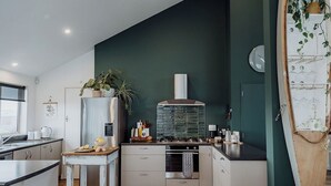A modern kitchen with a dark green accent wall, stainless steel appliances, and a wooden island.
