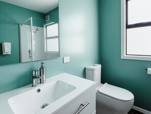 Un baño con lavamanos, espejo e inodoro blancos.