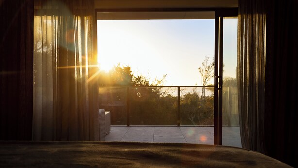 A room with a view of the outdoors through a large window, a bed, and a small table. - The Sundowner Beach Club (Hokitika)